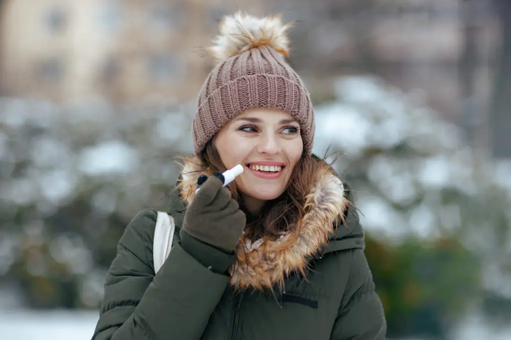 Woman applying chapstick during winter